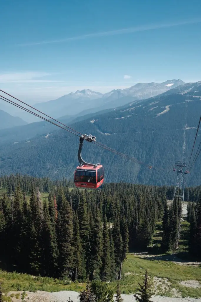 red gondola over a vast forest and mountains