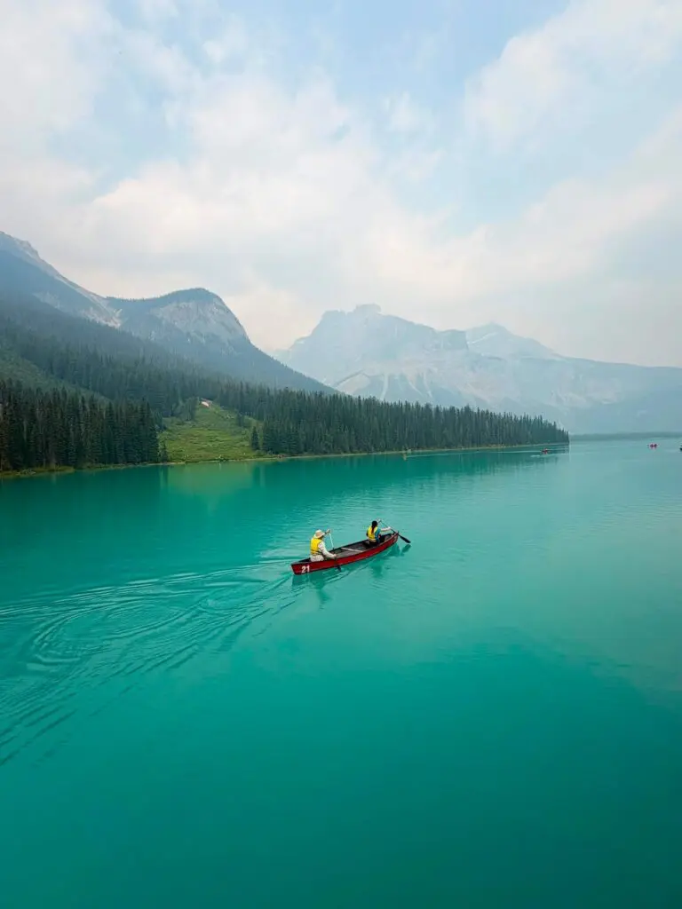two people paddling a red canoe on a turquoise lake in Canada
