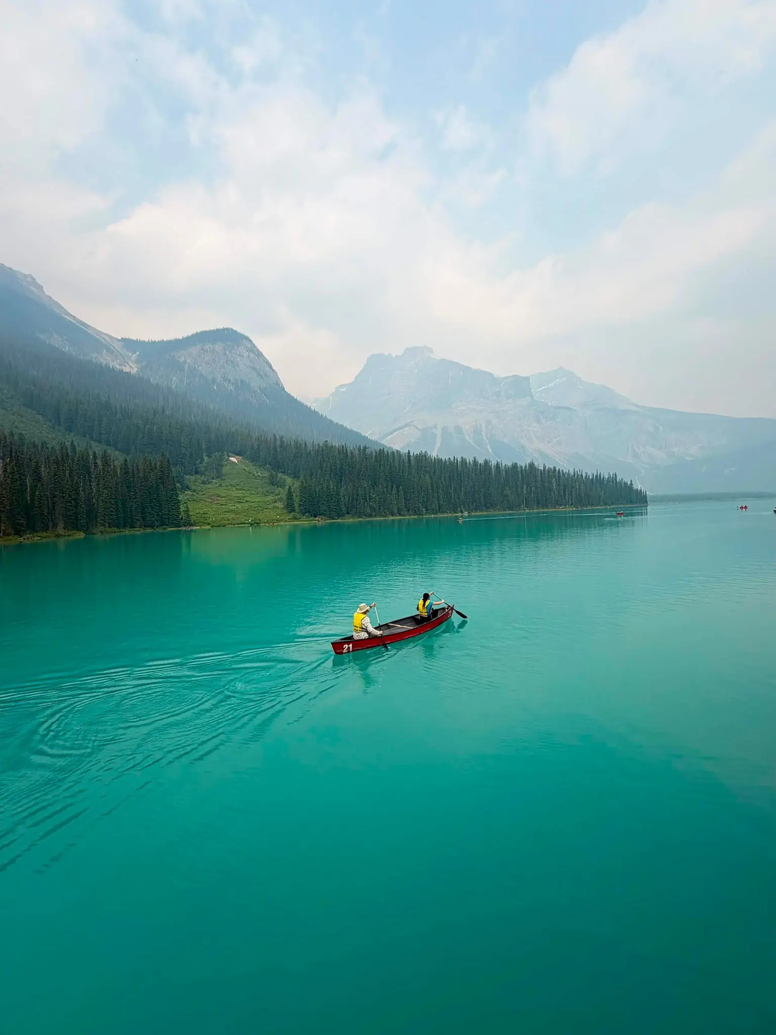two people paddling a red canoe on a turquoise lake in Canada