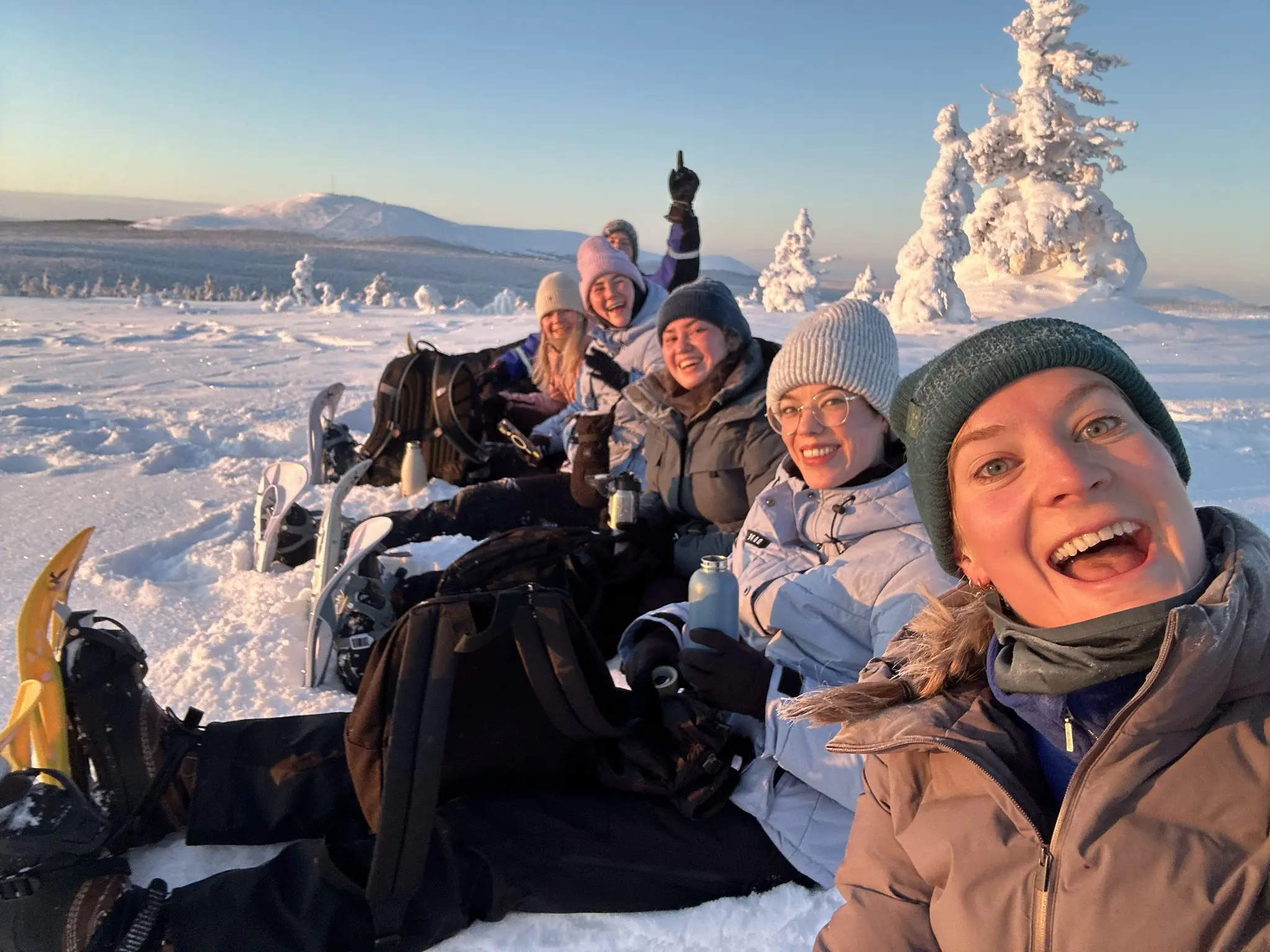 group of friends snowshoeing in snowy Lapland landscape at sunset