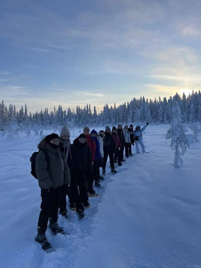 group of people snowshoeing in a snowy forest landscape