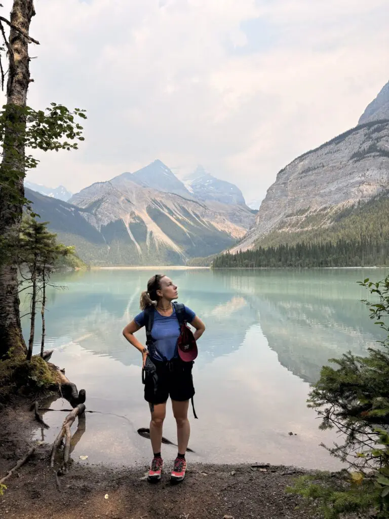 hiker looking up at mountains by a turquoise lake