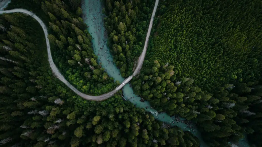 aerial view of winding road, river, and dense forest in Canada