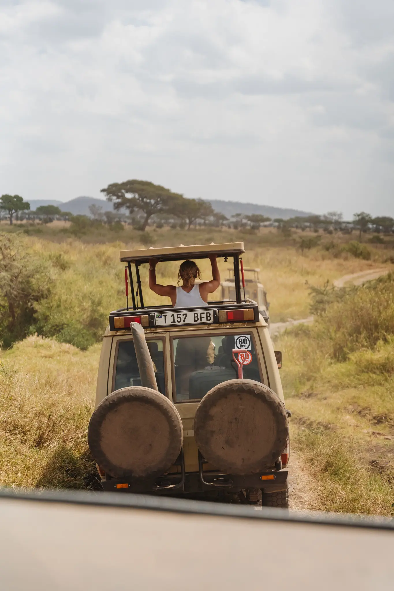 woman standing in safari jeep on a dusty road