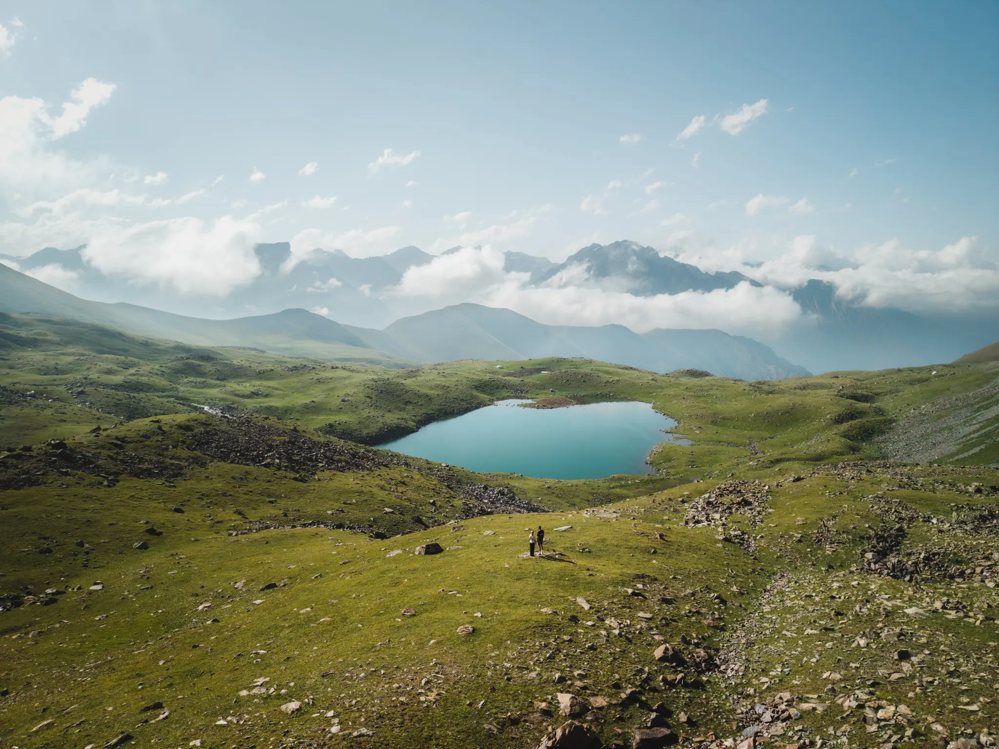 drone shot of two people by a mountain lake in Kyrgyzstan