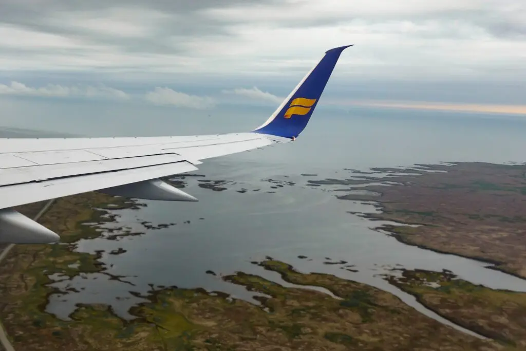 airplane wing over a marshy coastline from above