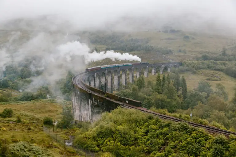 steam train on Glenfinnan Viaduct in misty Scottish Highlands