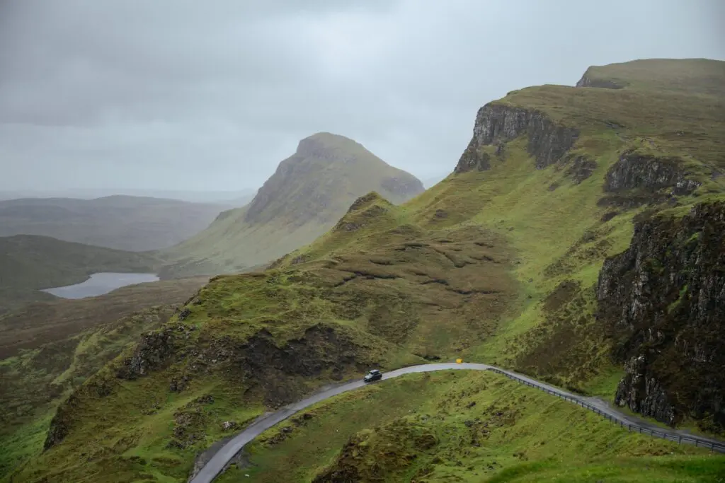 car driving on winding road through green Scottish mountains