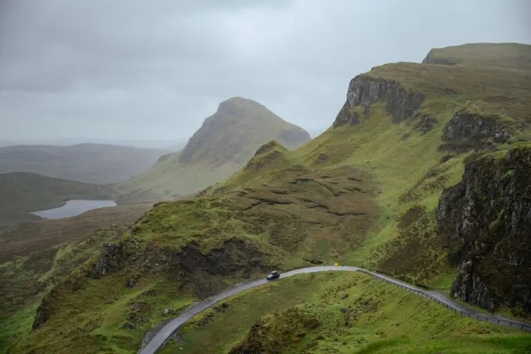 car driving on winding road through green Scottish mountains