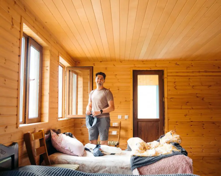 man standing in a rustic wooden cabin room