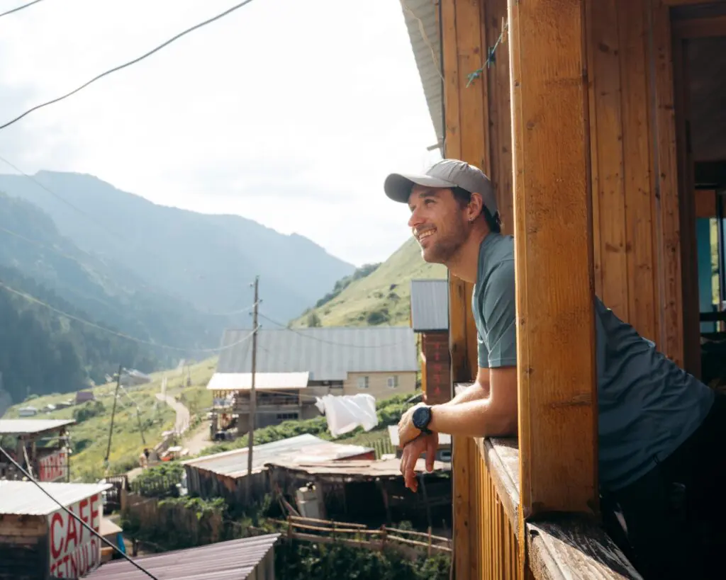 man smiling on balcony overlooking mountain village in Georgia