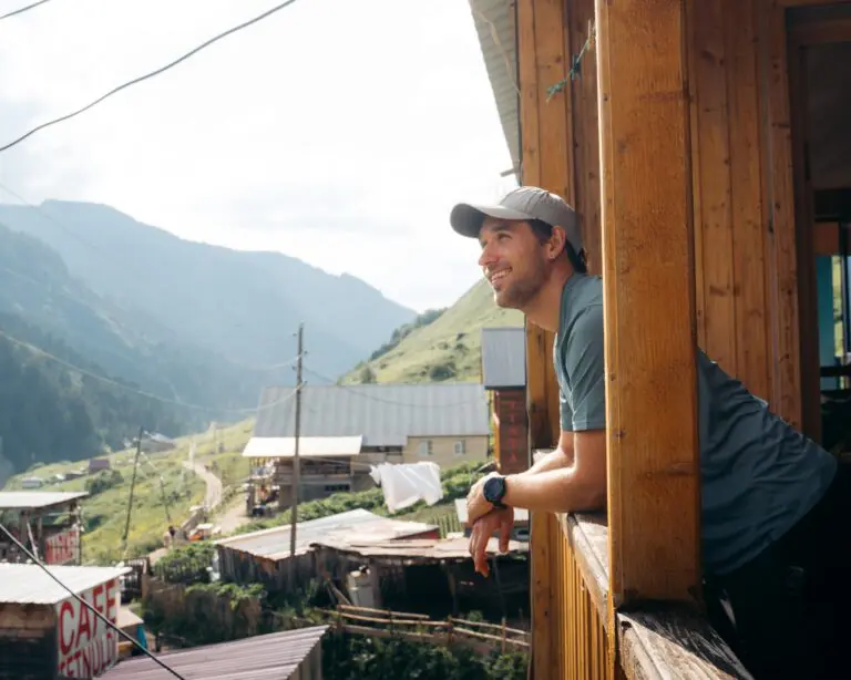 man smiling on balcony overlooking mountain village in Georgia