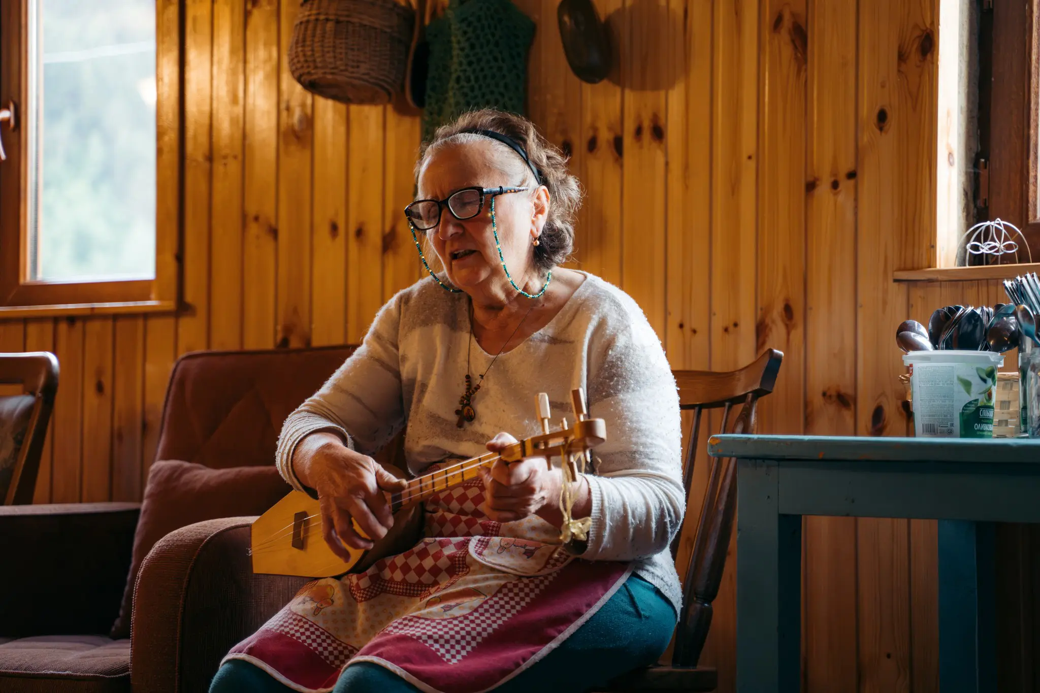 elderly woman playing traditional string instrument indoors