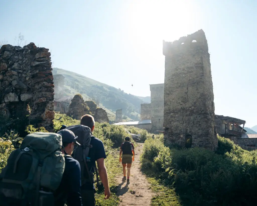 hikers walking past ancient stone towers in a mountain village