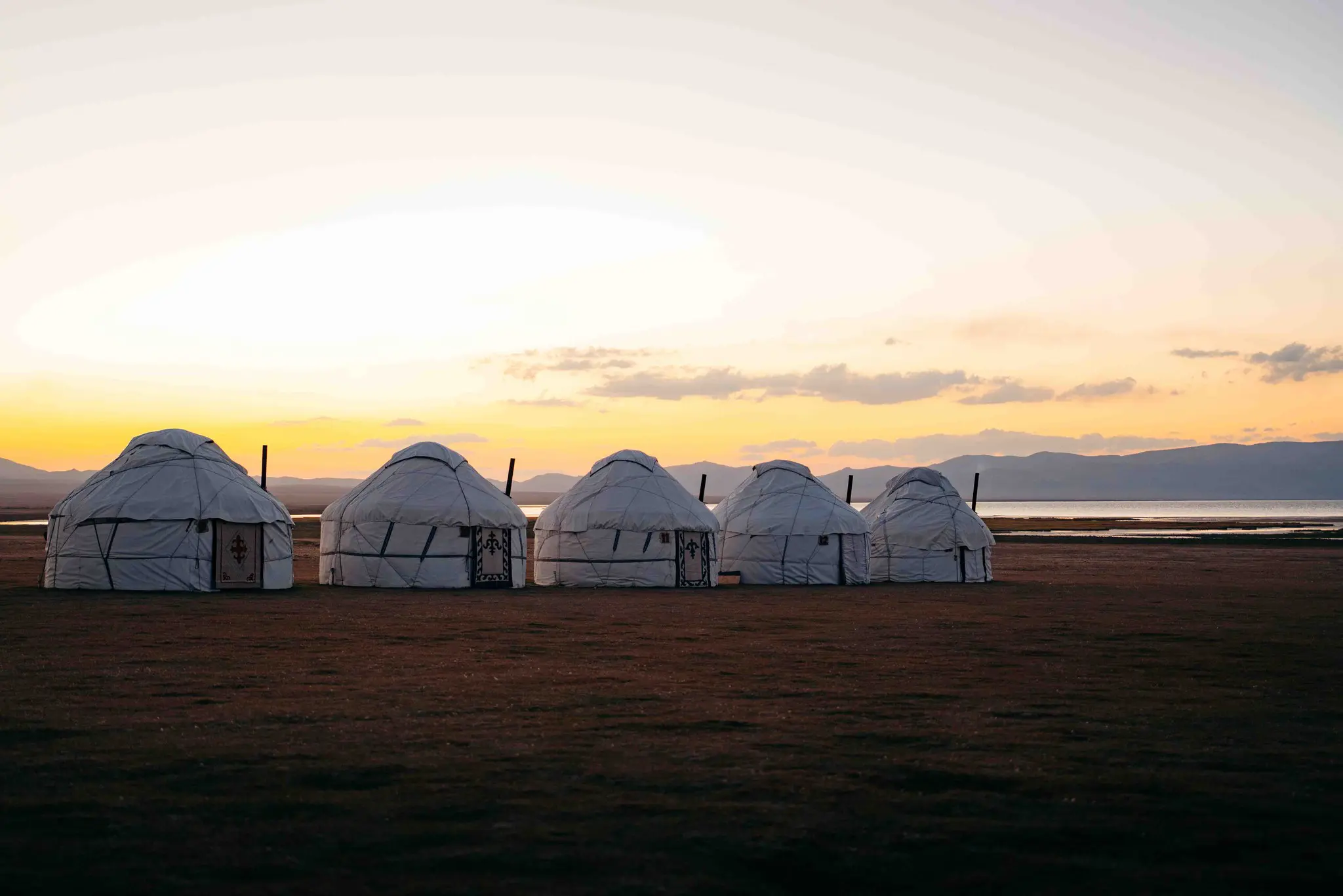 row of yurts at sunset by a lake in Kyrgyzstan